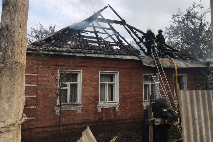 Разрушенный обстрелом дом в Дергачах и спасатели